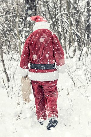 Santa Claus in snow storm holding presents bagの写真素材