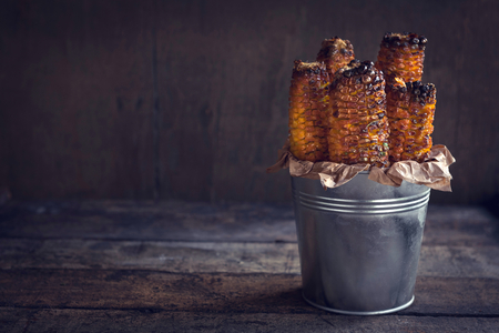 Grilled with corn in metal basket on wooden background with blank spaceの写真素材