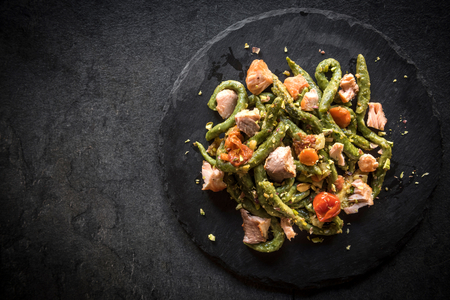 Salmon and spinach spaghetti served on dark background with blank spaceの写真素材