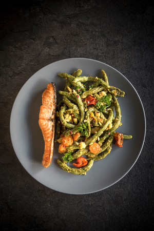 Salmon and spinach spaghetti in the plate on dark backgroundの写真素材
