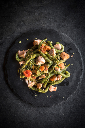 Sliced salmon and spinach spaghetti served on the dark backgroundの写真素材