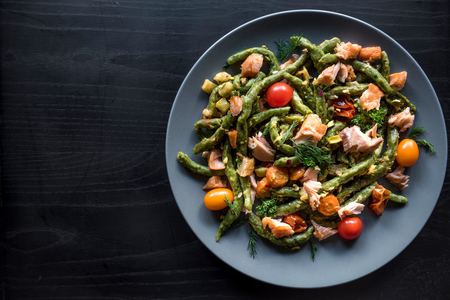 Salmon and spinach spaghetti served on wooden background with blank spaceの写真素材
