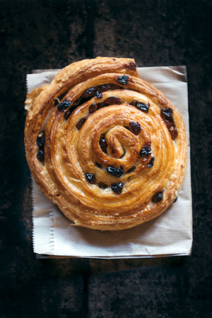 Baked pastry with dried grapes on wooden background,selective focus の写真素材
