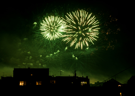 Green fireworks celebration at city night backgroundの写真素材