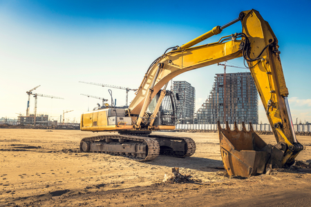 Excavator on construction site with bulldings in background,selective focus の写真素材