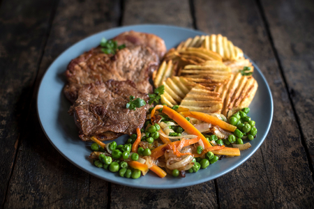 Pork steak,potatoes chips and vegetables served in the table,selective focus の写真素材