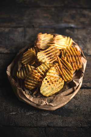 Fresh baked potatoes chips served on the wooden table,selective focus の写真素材