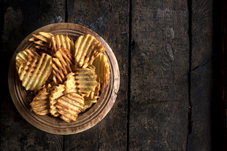 Served fresh baked potatoes chips on wooden background with blank space の写真素材