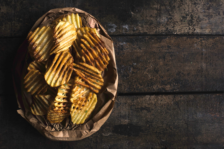 Homemade and baked potatoes chips on the wooden background with blank space の写真素材