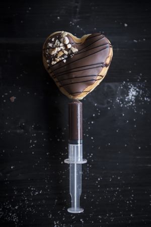 Injection with chocolate cream in heart shape donut,selective focus の写真素材