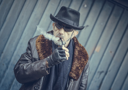 Fashionable man holding smoking pipe,selective focus の写真素材