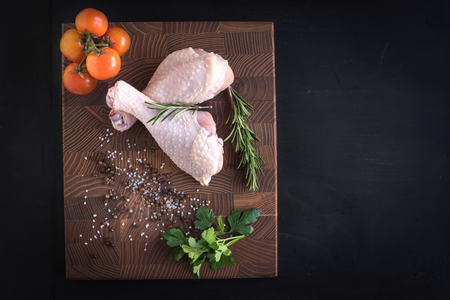 Raw chicken drumsticks on dark background with blank space の写真素材