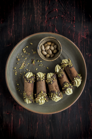 Traditional Italian dessert cannoli with pistachios served on the wooden background の写真素材