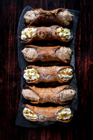 Traditional Italian dessert cannoli with chocolate and pistachios on the table,selective focus の写真素材