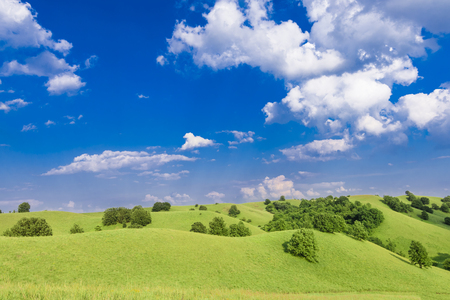 Landscape of the bright sky with clouds and green hillsの写真素材
