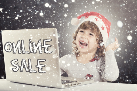 Happy little child with Santa hat and laptop computer,holiday online saleの写真素材