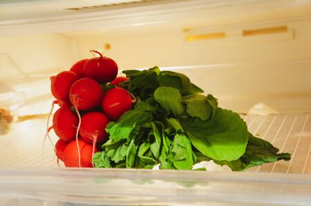 a bunch of fresh radishes on the shelf of the refrigerator