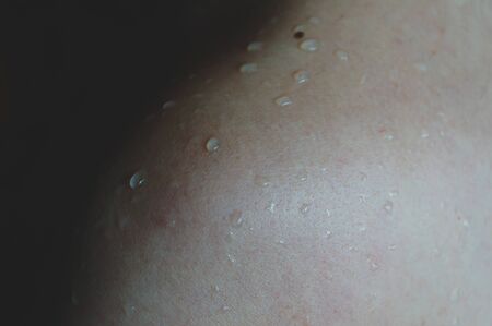 naked female shoulder with water drops