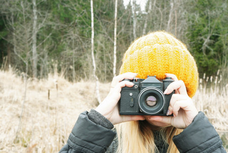 young girl Photographer in a hat with a vintage camera shoots framesの写真素材