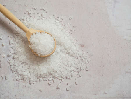 sea salt, a pile of sea salt in a wooden spoon on a light concrete backgroundの写真素材