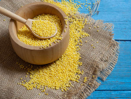 Millet. Millet in a wooden spoon and bowl on a wooden kitchen tableの写真素材