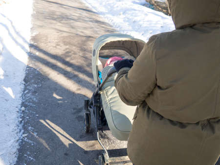 a girl in a winter frosty day rolls a baby stroller with a childの写真素材
