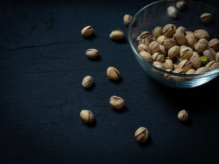 pistachios in a clear glass bowl on an old wooden table, an atmospheric rustic composition, a copy spaceの写真素材