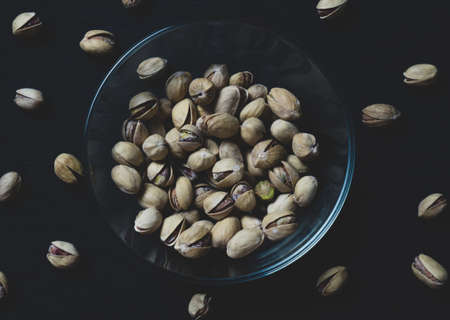 pistachios in a clear glass bowl on an old wooden table, an atmospheric rustic composition, a copy...