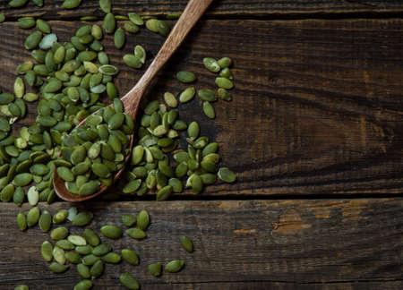 Pumpkin seeds in a wooden spoon on an old wooden table. copying text spaceの写真素材