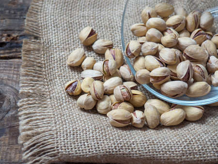 pistachios in a clear glass bowl on an old wooden table, an atmospheric rustic composition, a copy...