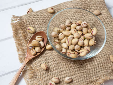 pistachios in a clear glass bowl on an old wooden table, an atmospheric rustic composition, a copy...