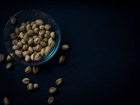 pistachios in a clear glass bowl on an old wooden table, an atmospheric rustic composition, a copy spaceの写真素材