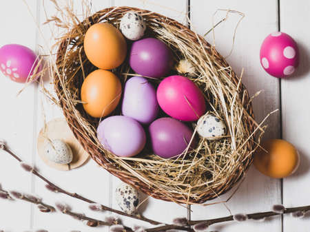 Easter eggs, in a nest on a white wooden background. The minimal concept of Easter. Top view. An Easter card with a copy of the place for the text.の写真素材