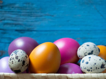 Colorful Easter eggs in a basket on an old wooden background with space for your textの写真素材