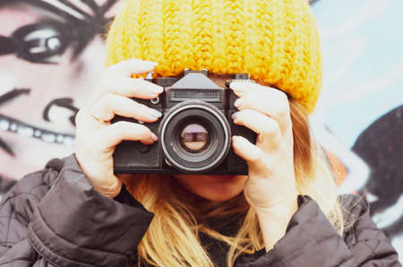 young girl Photographer in a hat with a vintage camera shoots frames