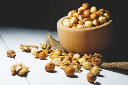 Assortment of nuts in a wooden bowl on the table. hazelnuts and walnuts healthy eating conceptの写真素材