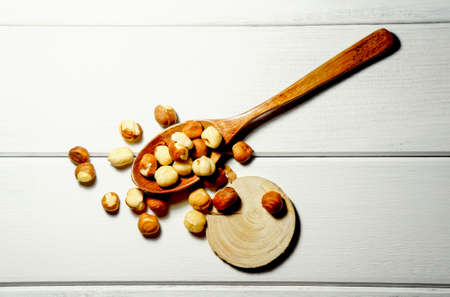 hazelnuts on a wooden spoon on a white wooden tableの写真素材