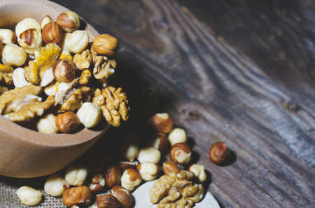 walnuts and hazelnuts on a spoon on a wooden table, concept of healthy eatingの写真素材