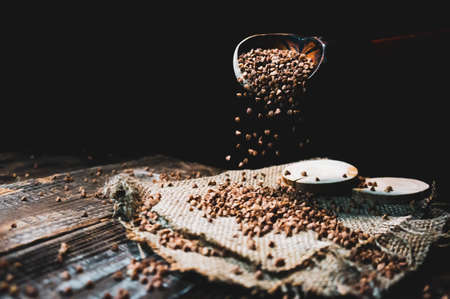 buckwheat in a wooden bowl and an old spoon on the tableの写真素材