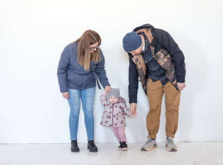 Modern young family, mom, dad and their eight-month-old daughter hold hands