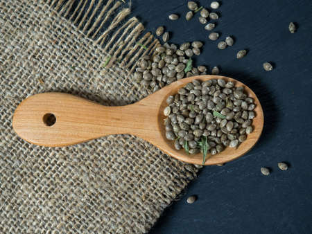 Hemp seeds in a wooden spoon on a black wooden tableの写真素材
