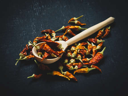 dried chili pepper on a wooden spoon on a dark background, space for textの写真素材