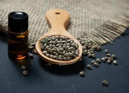 Hemp seeds in a wooden spoon on a black wooden tableの写真素材