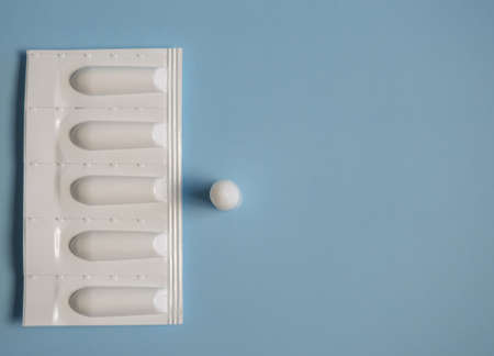 Suppository for anal or vaginal use on a blue background. Candles for the treatment of hemorrhoids,...