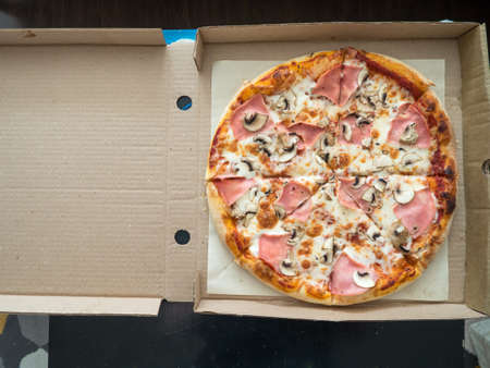 pizza in an open box is on the table in the room