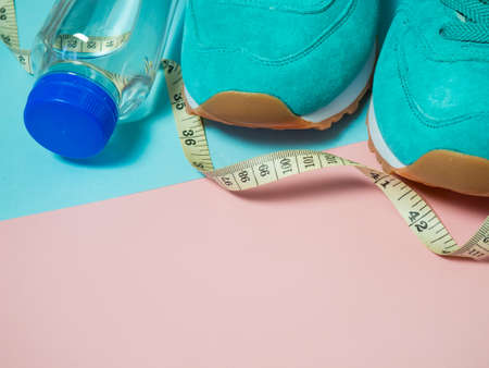 turquoise sneakers and a bottle of water on a pink background. The concept of a healthy lifestyle,...