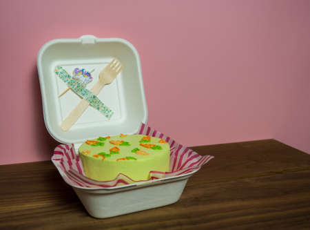 a small cake in a paper box with a fork and a candle, a holiday for two, a copy of the spaceの写真素材