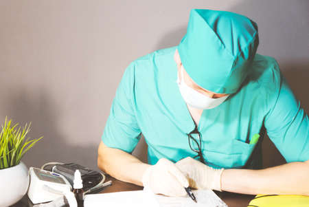 doctor in surgical mask and protective gloves looks at the tablet
