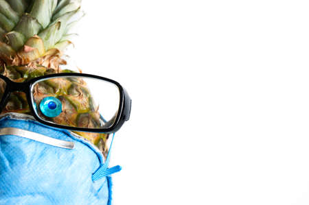 Pineapple in a mask respirator filter and glasses on a white background - Global impact concept COVID-19の写真素材