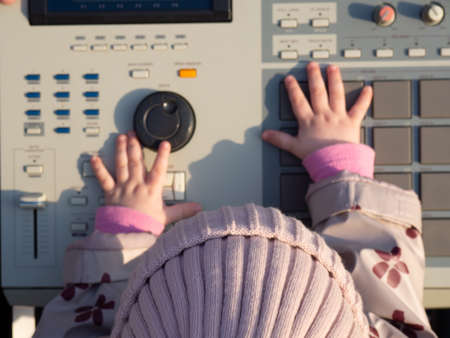 a toddler presses buttons on an electronic musical instrument, a drum machine for creating hip-hop instrumentsの写真素材